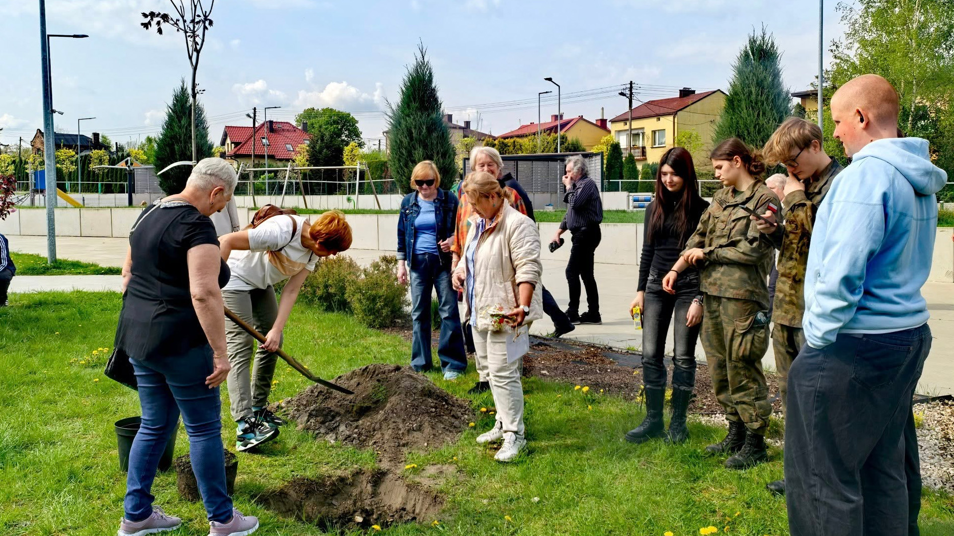 Osoby w różnym wieku wspólnie sadzą drzewo – lokalne działanie społeczne