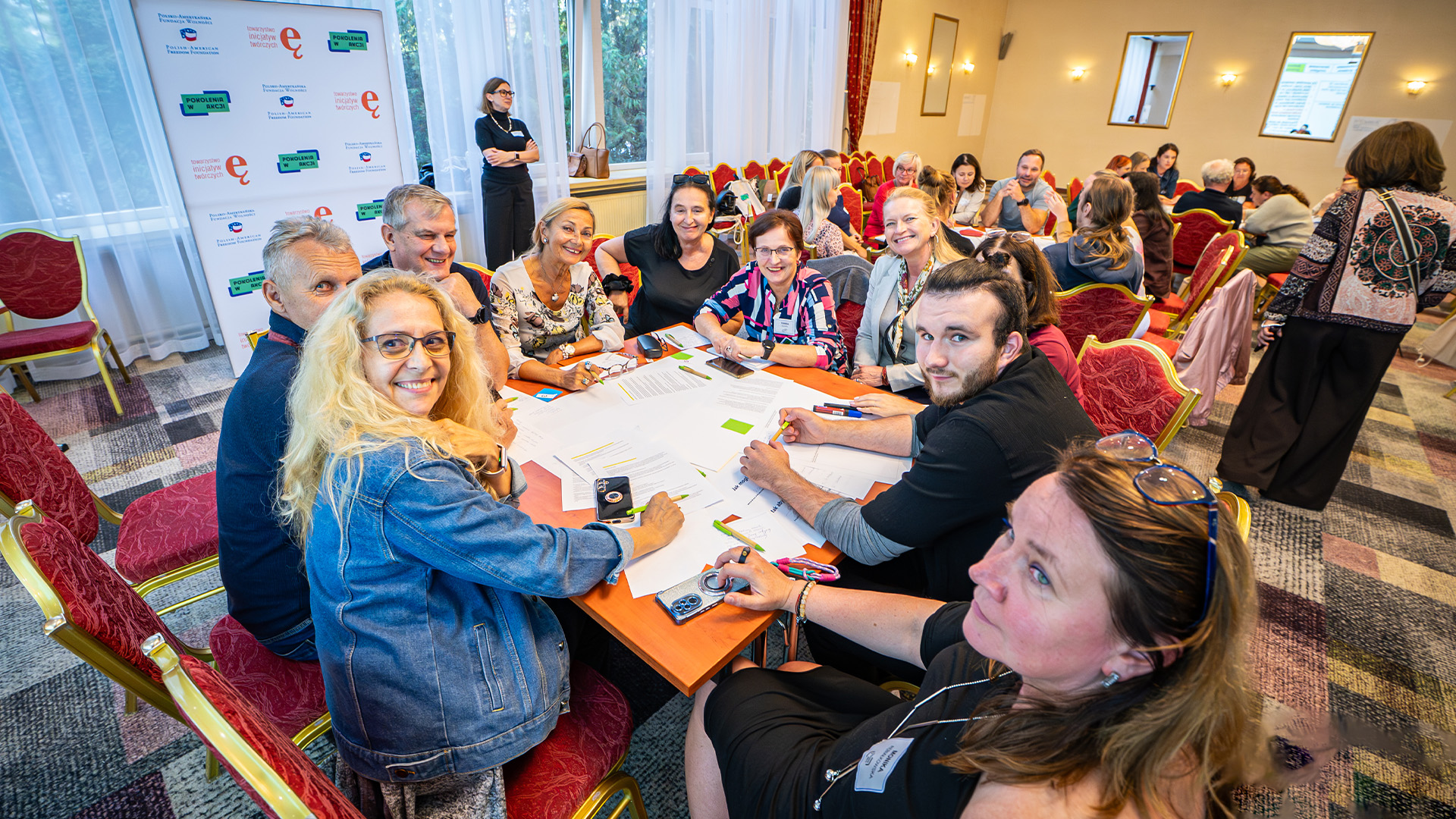 Grupa uczestniczek i uczestników programu Pokolenia w Akcji pracuje wspólnie przy stole